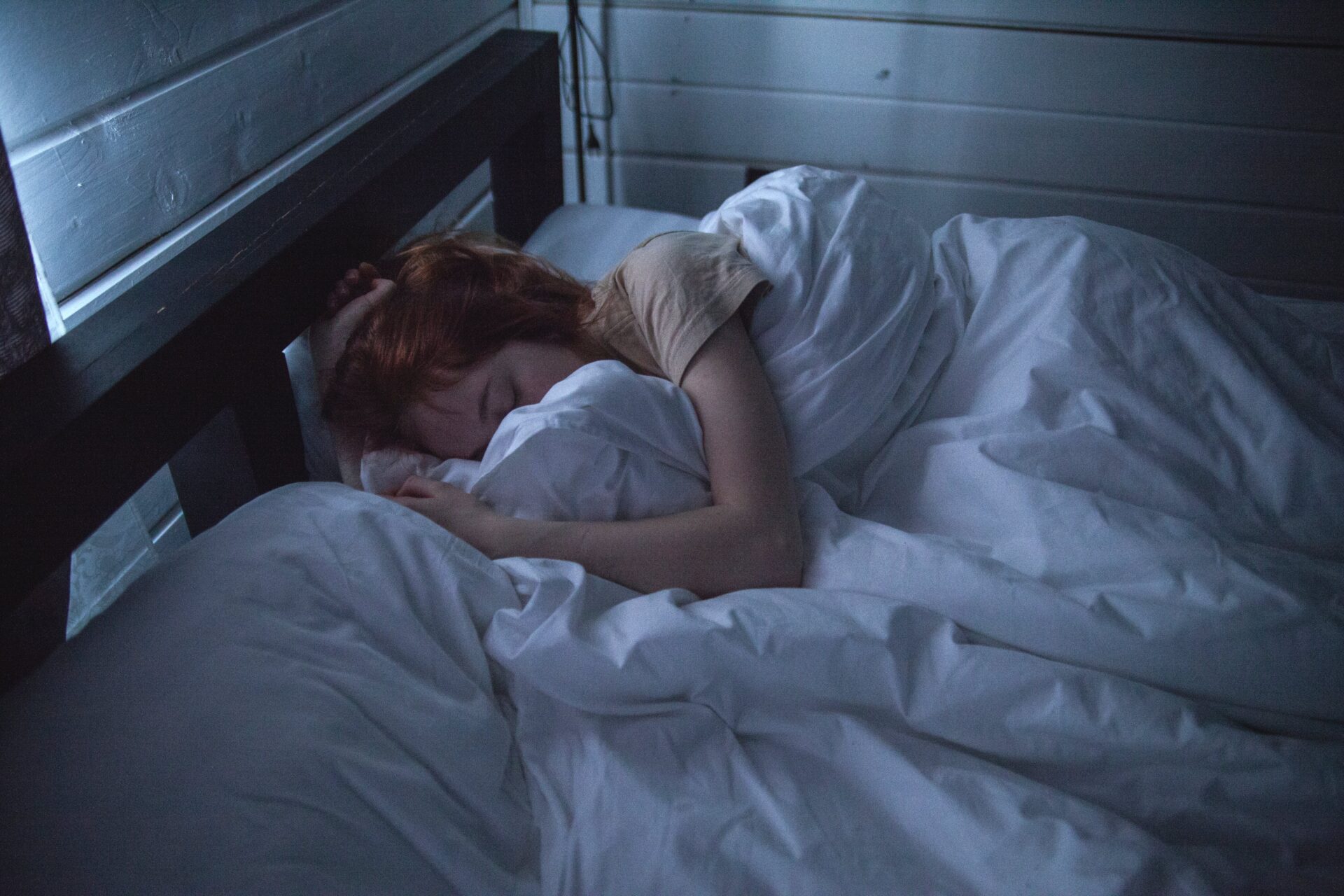 ベッドの上で布団にくるまって眠る女性の写真