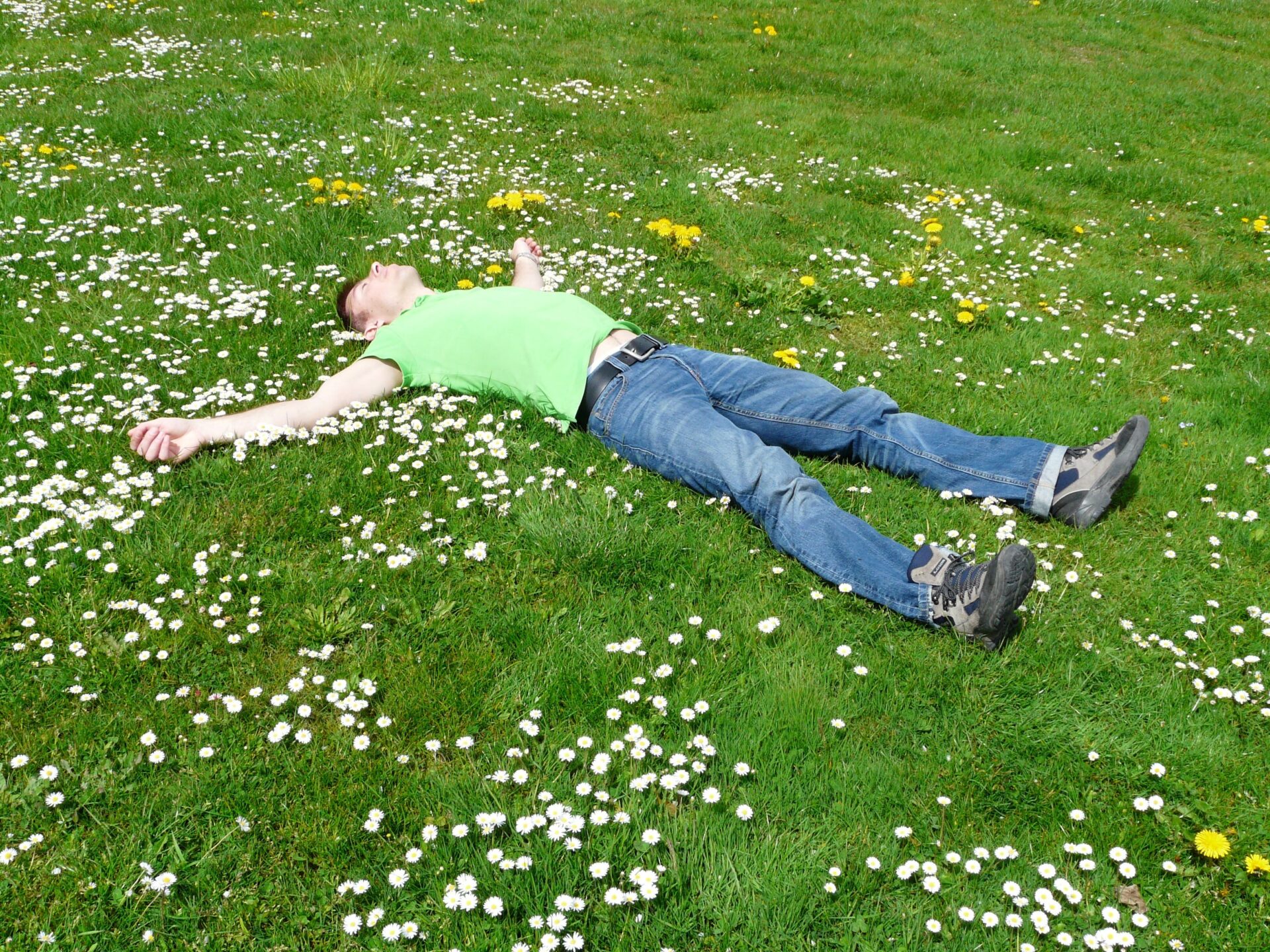 緑の芝生の上で大の字で休む男性の写真